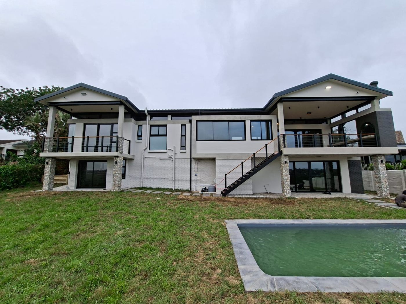 Rear elevation of the renovated Linkside home with balconies, lawn and swimming pool