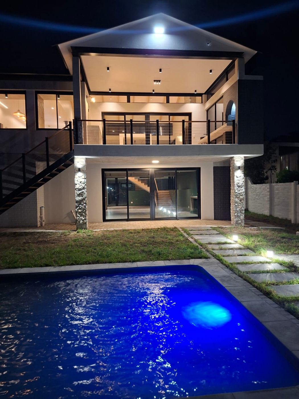 Pool and double-height glazed living area at House - Linkside at night