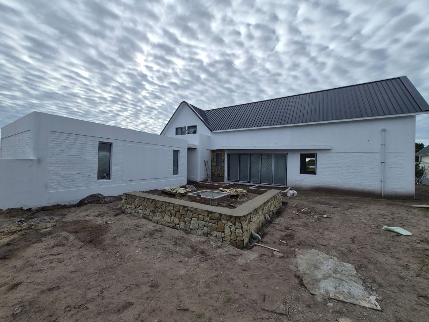 Single-storey side wing of House Thompson beside a stone-clad raised planter