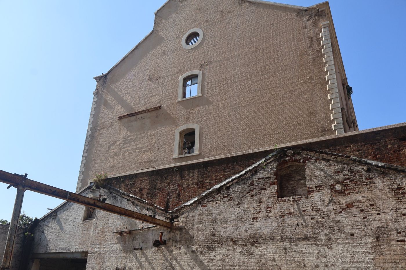 The mill's tall brick gable with arched windows, above an older lower roofline