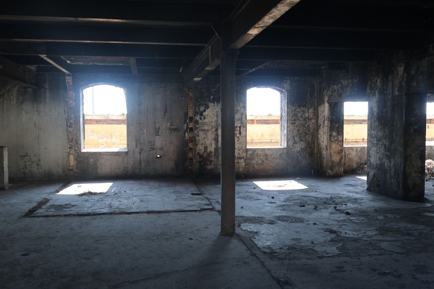 Dim upper-floor interior lit by three arched windows