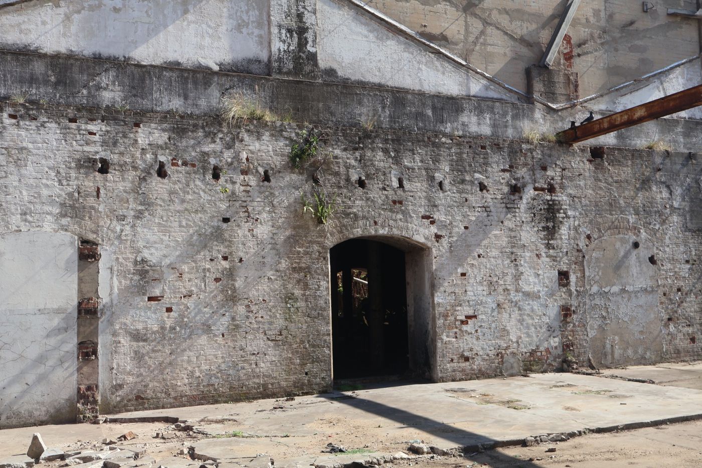 Thick masonry wall with an arched doorway inside the open mill structure