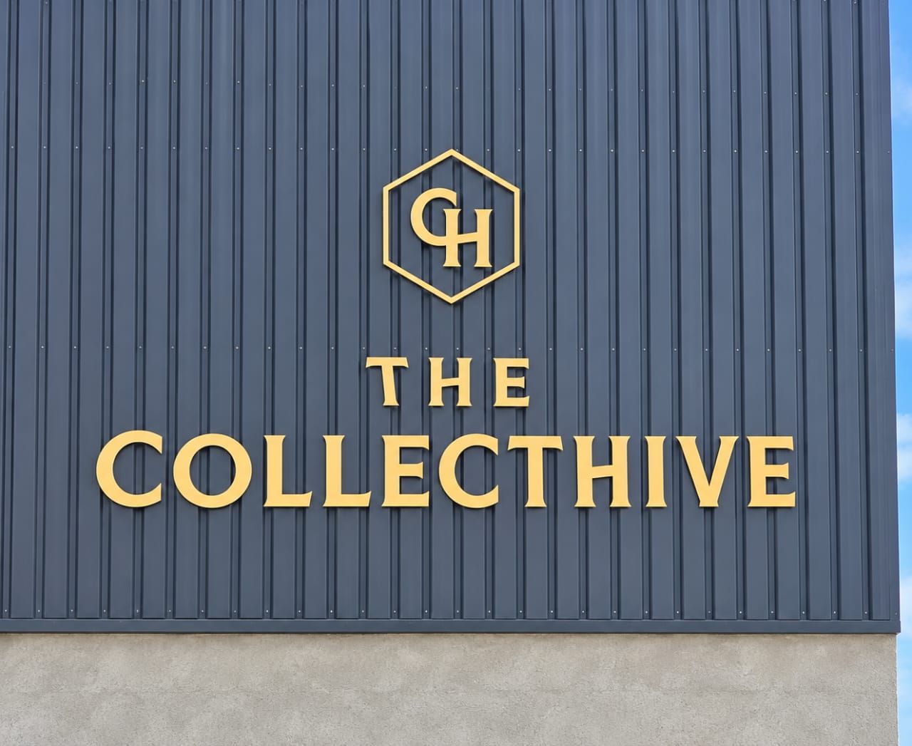 Gold 'The Collecthive' lettering and hexagon logo on dark ribbed cladding